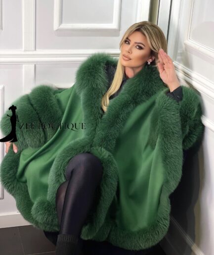 Woman wearing a green fur coat with a visible brand logo in an indoor setting.