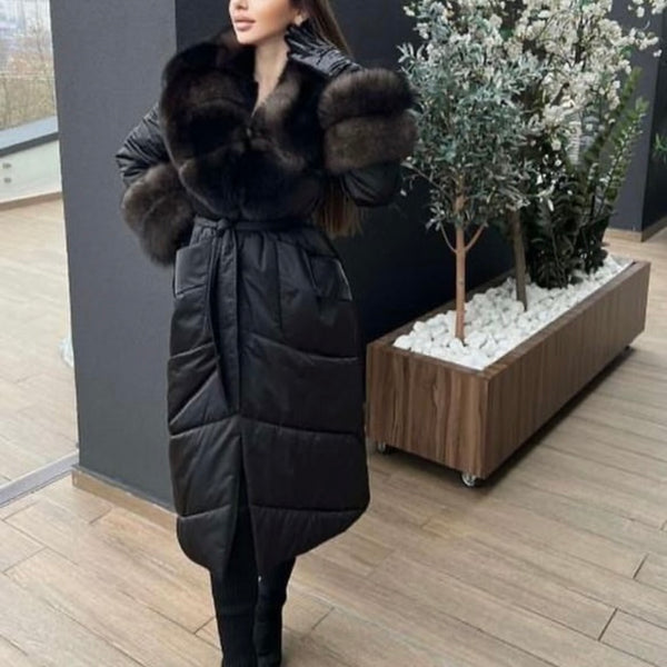 Woman wearing a black puffer coat with fur trim on a wooden deck.