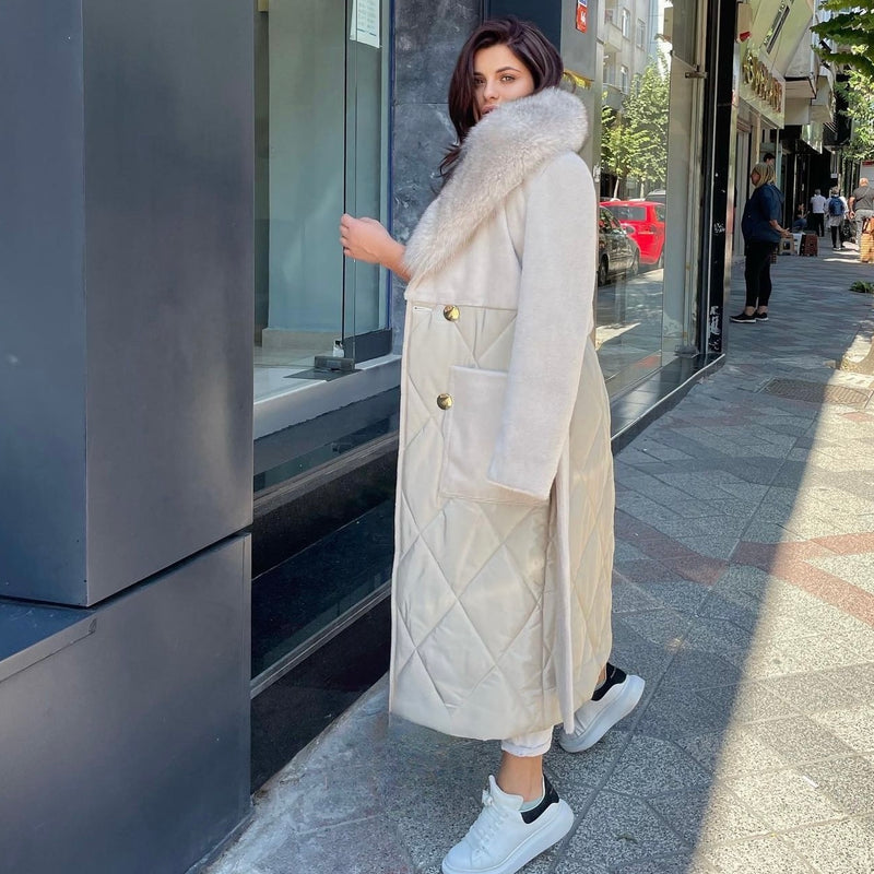 Woman wearing a long beige coat with fur hood on a city street.