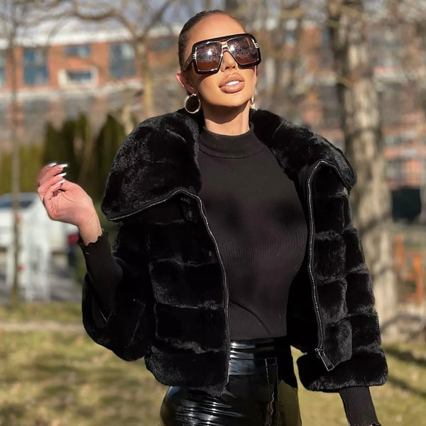 Woman wearing a black fur coat and sunglasses outdoors