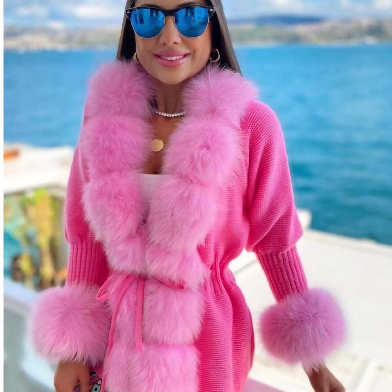 Woman wearing a pink outfit with fur trim by a waterfront