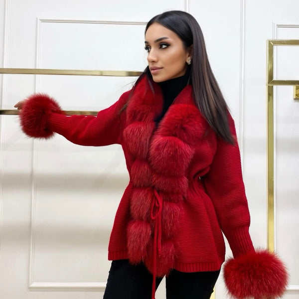 Woman wearing a red fur-trimmed coat against a white wall.