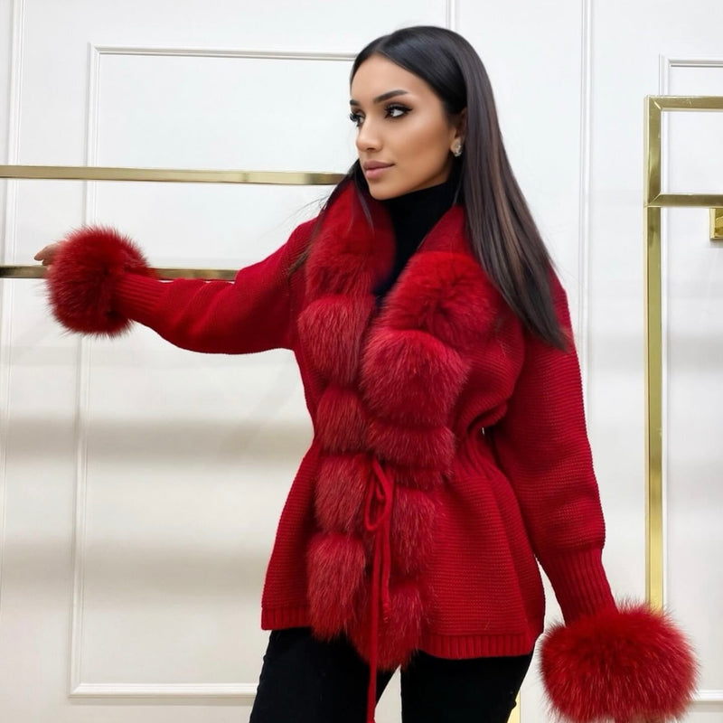 Woman wearing a red fur-trimmed coat against a white wall.