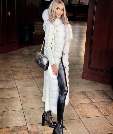 Woman wearing a long white puffer coat with fur trim in an indoor setting.