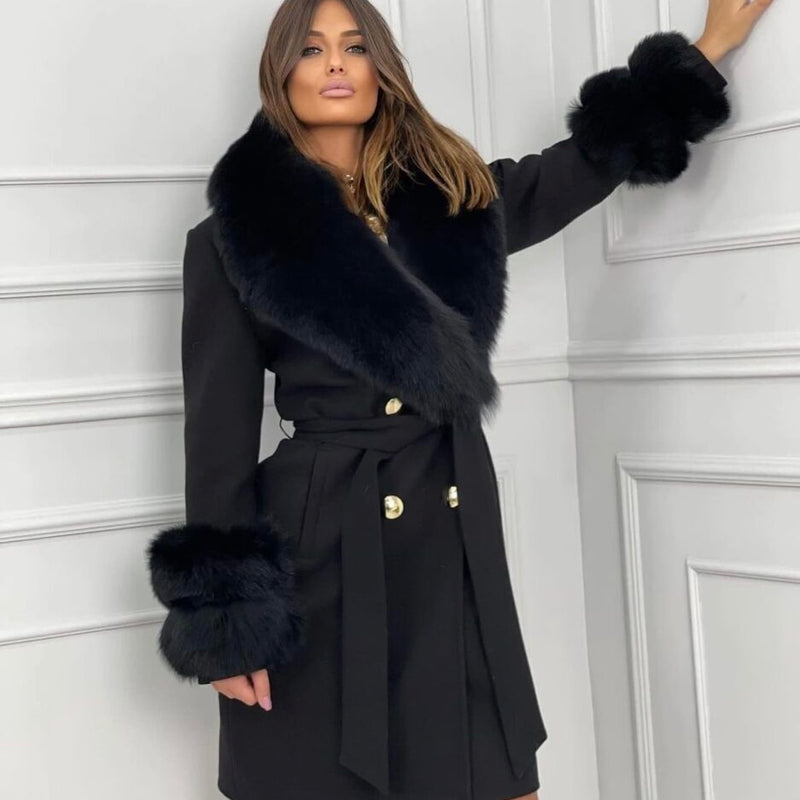 Woman wearing a black coat with fur trim against a white paneled wall
