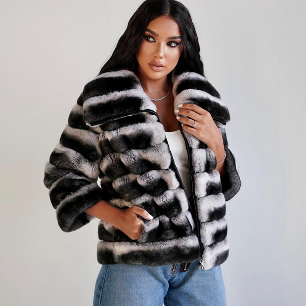 Woman wearing a black and white striped fur coat against a plain background