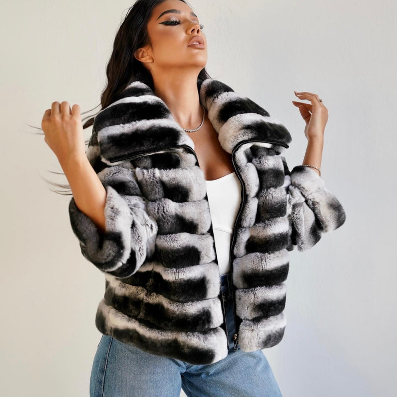 Woman wearing a black and white striped fur coat against a plain background