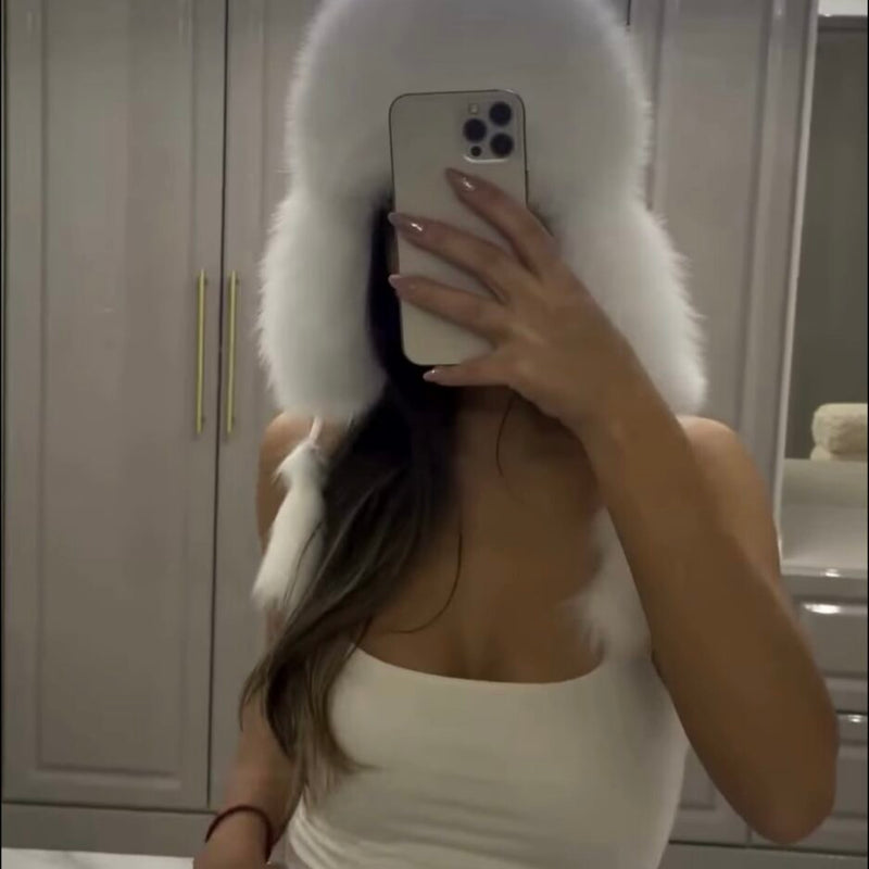 Person wearing a white fur coat taking a mirror selfie.