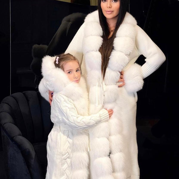 Two people wearing white fur coats against a dark background