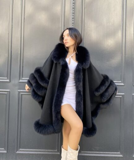 Woman wearing a black fur coat against a gray wall