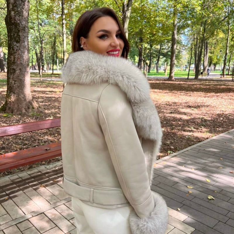 Woman wearing a beige leather jacket with fur trim in a park setting