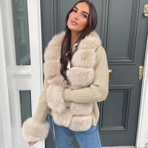 Woman wearing a beige fur-trimmed coat in front of a gray door.